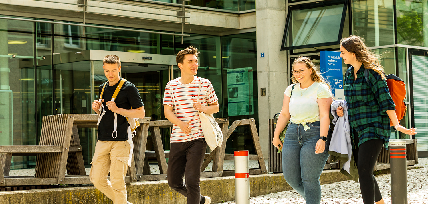 Vier Studierende laufen vor der Hochschulbibliothek