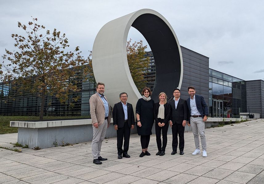 vor einem Loop Kunstwerk im Außenbereich steht eine Gruppe von 4 Männern und zwei Frauen und blicken in die Kamera