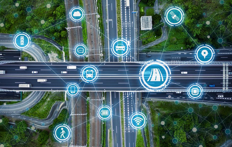 Straßenkreuzung aus Vogelperspektive, Straßen und Schienen, davor Symbole aus dem Bereich Verkehr und Digitalisierung