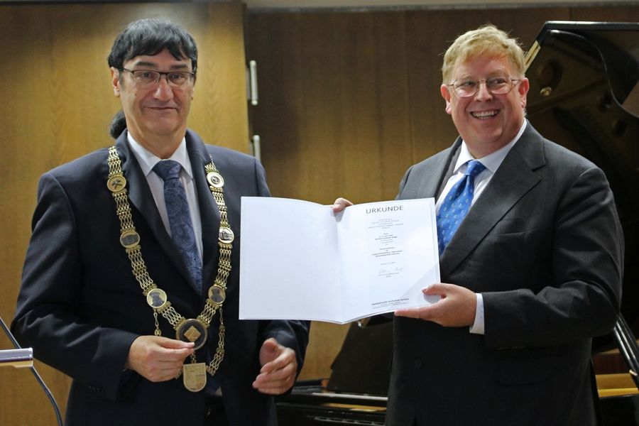 Rektor Prof. Kassel mit Amtskette und Honorar-Professor Dr. Bernhard Johannes Seliger präsentieren die Ernennungsurkunde. 