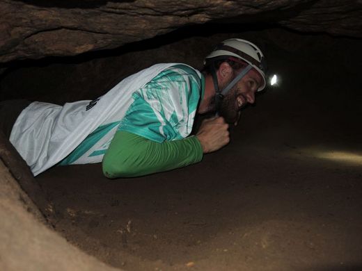 Foto: Outdoor. Ein Mann kriecht durch eine Höhle.
