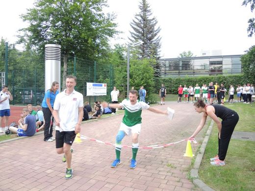 Foto: Sportfest. Zwei Teilnehmer laufen durch ein Ziel.