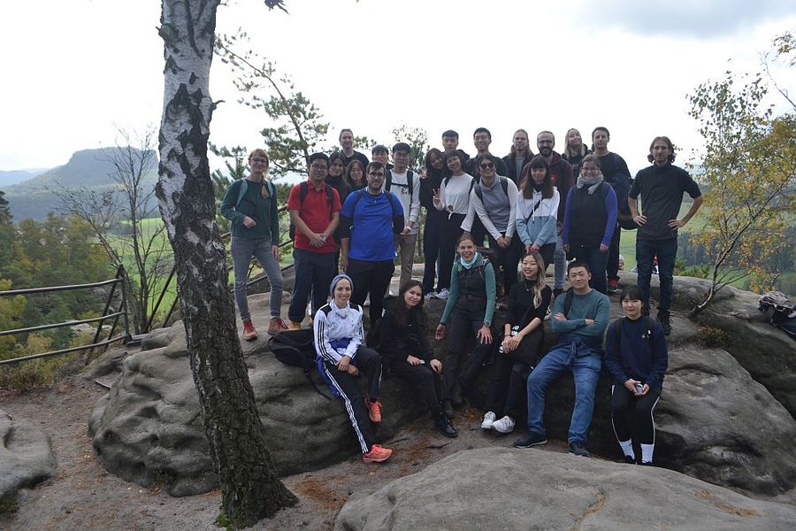 Foto: Eine Gruppe junger Menschen steht auf einem Berg im Elbsandsteingebirge. 