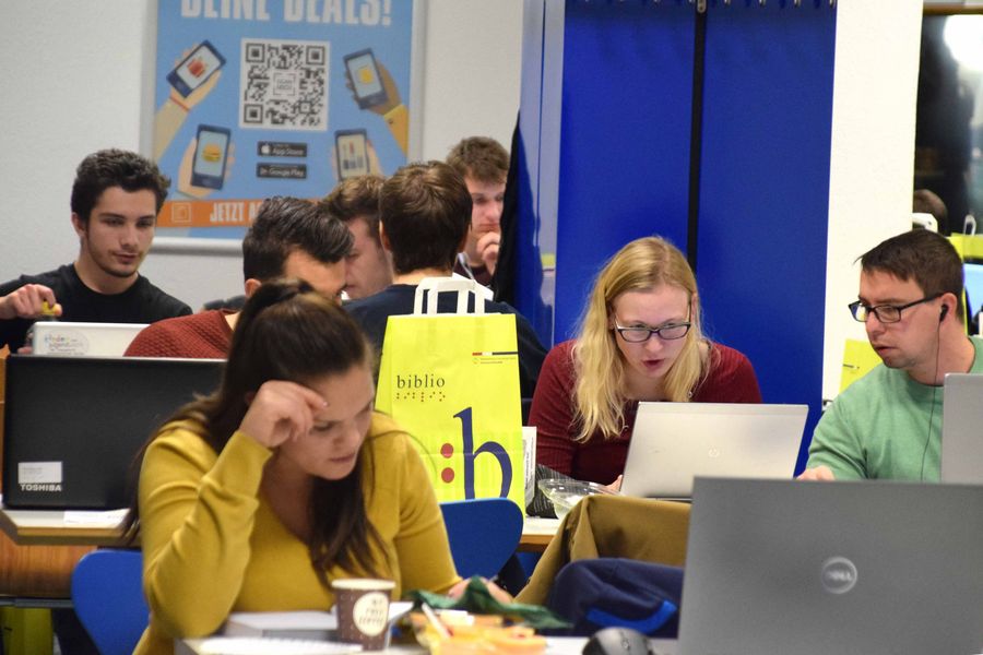 Foto: Teilnehmer bei der Nacht der aufgeschobenen Arbeiten, sitzen in der Mensa an den Tischen vor ihren Laptops.