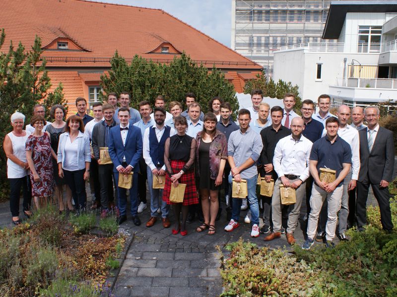 Gruppenbild der Absolventen, Professoren und Mitarbeiter auf einer Grünfläche