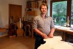 Ein Mann steht in einer Werkstatt, in der Musikinstrumente gefertigt werden.