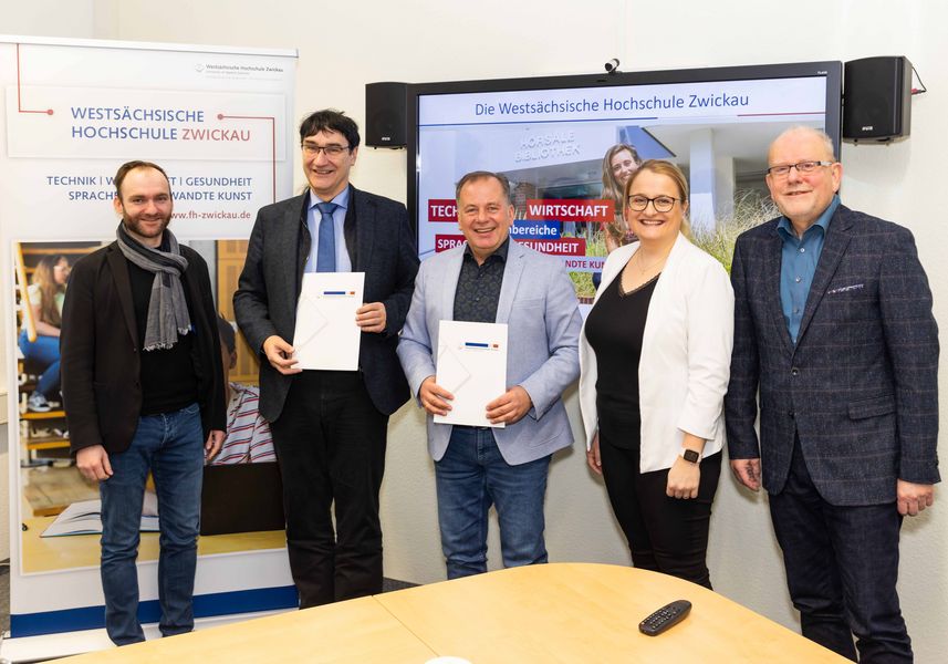Gruppenfoto mit WHZ-Mitarbeiter Markus Haubold (Verantwortlich für Stipendien), Rektor Prof. Stephan Kassel, N+PGeschäftsführer Jens Hertwig, N+P Personalreferentin Stefanie Marggraff und Dr. Jörg Winterfeld, Referent des Rektorates für Hochschul- und Relationshipmanagement (v.l.). Im Hintergrund Screens und Werbetafeln der WHZ. 