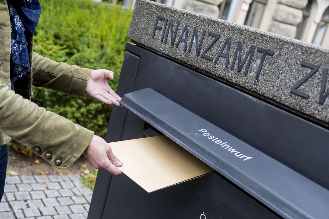 Foto: Ein Hand wirft einen Brief in den Postkasten des Finanzamt Zwickau.
