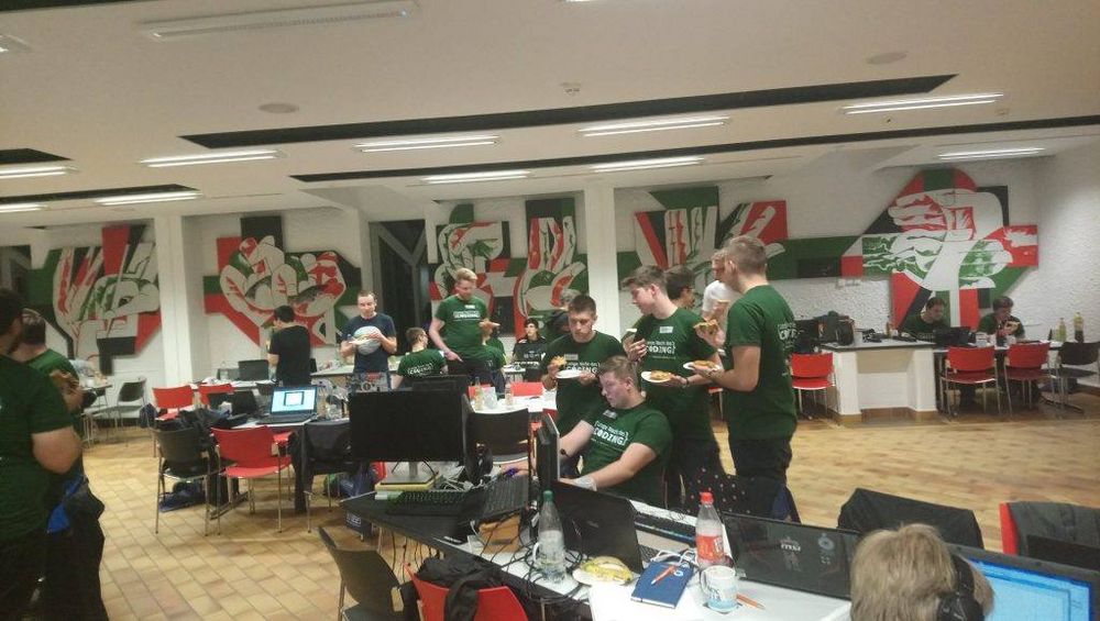 Foto: Teilnehmer der langen Nacht des Coding sitzen in der Mensa Scheffelberg mit ihren Laptops auf den Tischen und arbeiten.