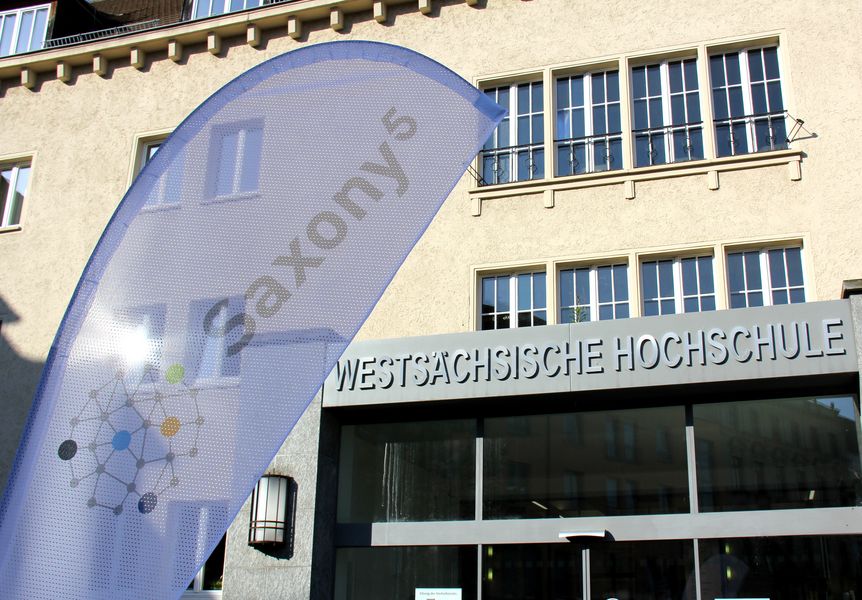 Foto: Eine Fahne mit der Aufschrift Saxony5 weht vor dem Eingang der Westsächsischen Hochschule
