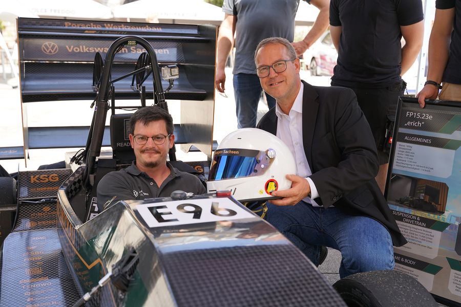 Fahrer im Rennwagen des Racing Teams, Übergabe eines Helmes