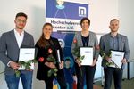 Absolventen zeigen ihre Urkunden, dahinter ein Aufsteller des Hochschulvereins Mentor