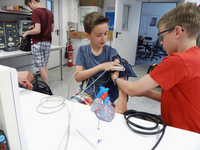 Foto: In einem Medizintechniklabor legt ein Schüler seinem Schulkamerad ein Blutdruckmessgerät am Oberarm an.