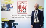 Ein Mann im Anzug steht vür einem Logo der "IIW Annual Assembly and International Conference on Welding and Joining", Tokyo 2022
