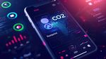 Smartphone displaying CO2 footprint tracking app with data analytics and world map visualizations. Environmental impact monitoring, carbon footprint reduction, sustainability