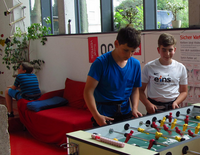 Foto: Zwei Schüler stehen an einem Tischfussball Spielgerät und spielen miteinander.