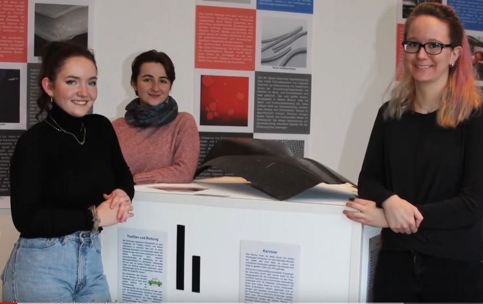 Foto: Gruppenbild, Personen um einen Stand schauen in die Kamera
