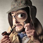 Foto: Eine Person im Sherlock Homes Kostüm schaut durch eine Lupe in die Kamera. Dabei wirkt das Auge vergrößert.