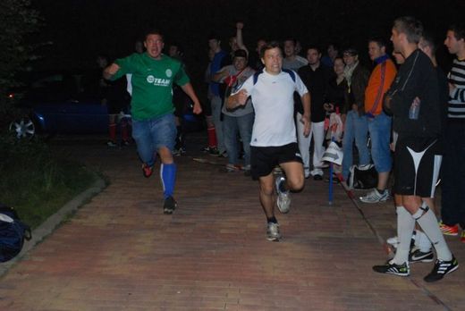 Foto: Zwei Läufer rennen an einer Gruppe Zuschauer vorbei.