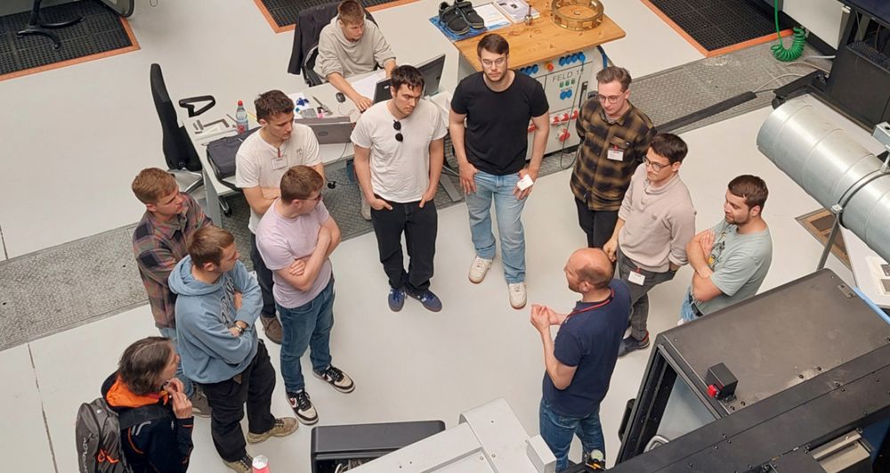 Ansicht von oben auf Gruppe Studenten und Mitarbeiter vor Maschine