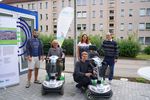 Foto: Vorn sitzt ein Mann auf einem Elektroscooter, daneben hockt ein Mann neben einem Elektroscooter. Dahinter stehen ein Mann, eine Frau und ein Mann.