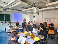 Foto: Teilnehmende Studierende am Deutsch-Intensivkurs sitzen an Tischen und lernen Deutsch