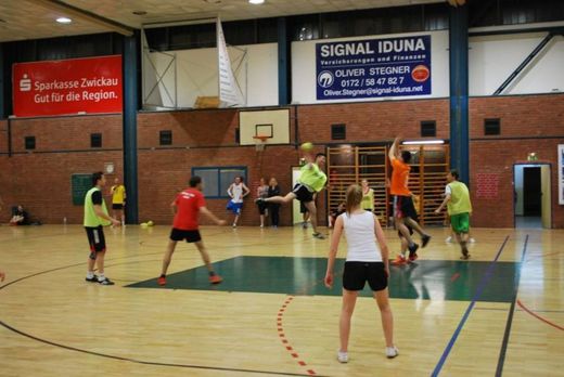Foto: Spieler beim Handballspiel in einer Sporthalle.
