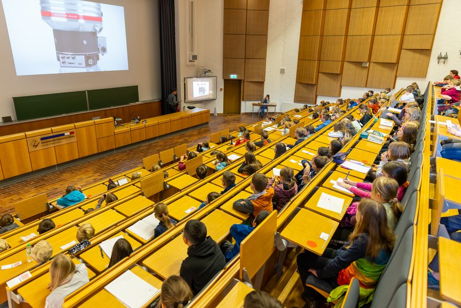 Blick in den vollen Hörssal 1. Die Kinder schauen gebannt zu. 