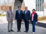 Vier Personen stehen auf dem Campus nebeneinander.