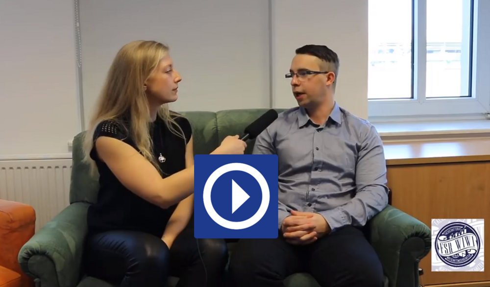 Videovorschaubild. Link zum Video. Studentin Lena vor Ort interviewt auf einem Sofa sitzend ein Mitglied des Fachschaftsrates.