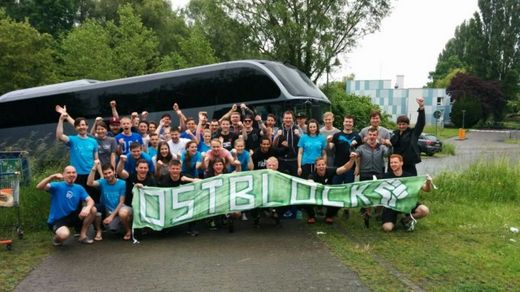 Foto: Gruppenbild. Teilnehmer vom Hochschulsport mit einem Banner, welches die Aufschrift trägt "Ostblock".