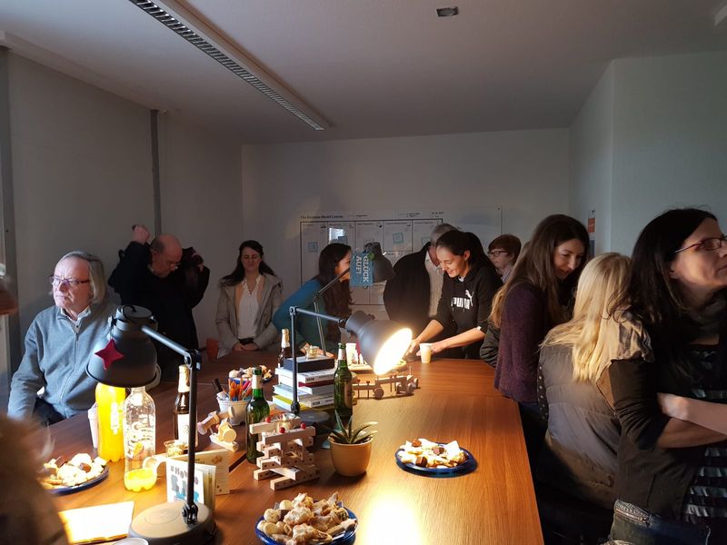 Foto: Mehrere Personen zur Eröffnung des "BergWork" haben sich stehend und sitzend iin einem Raum um eine Tischtafel versammelt und kommunizieren miteinander.