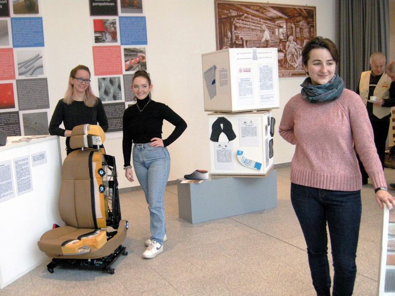 3 Studentinnen stehen in der Ausstellung, der Blick ist in die Kamera gerichtet