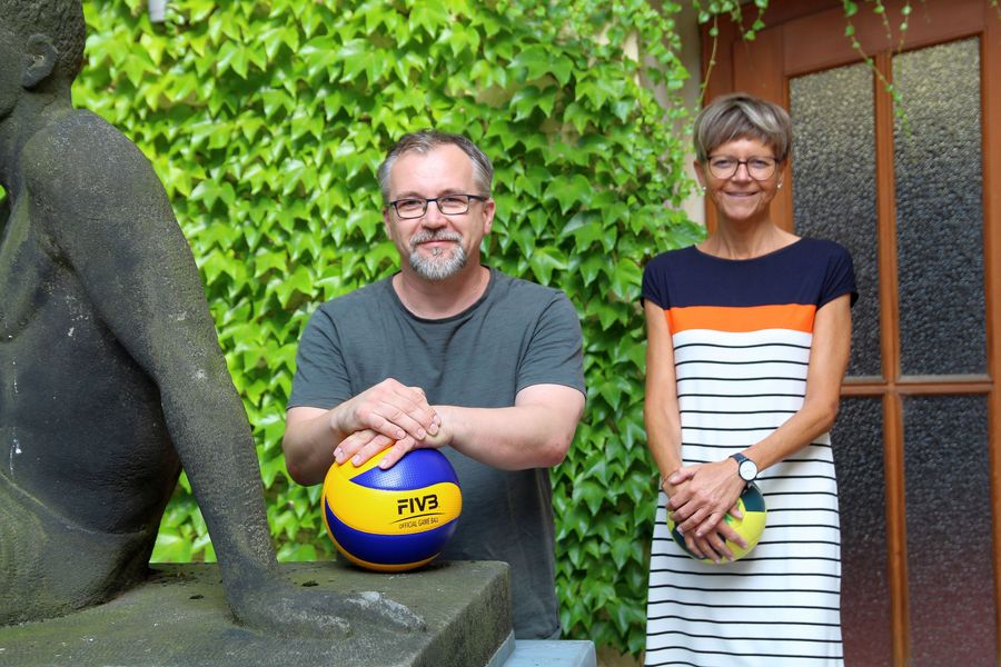 Ein Mann und eine Frau halten Bälle in der Hand und blicken in die Kamera. 