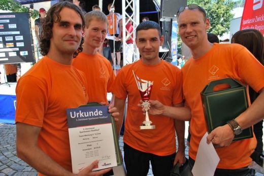 Foto: Ein 4 Personen Team des Sparkassen Stadtlaufes zeigt seinen Pokal und eine Urkunde.