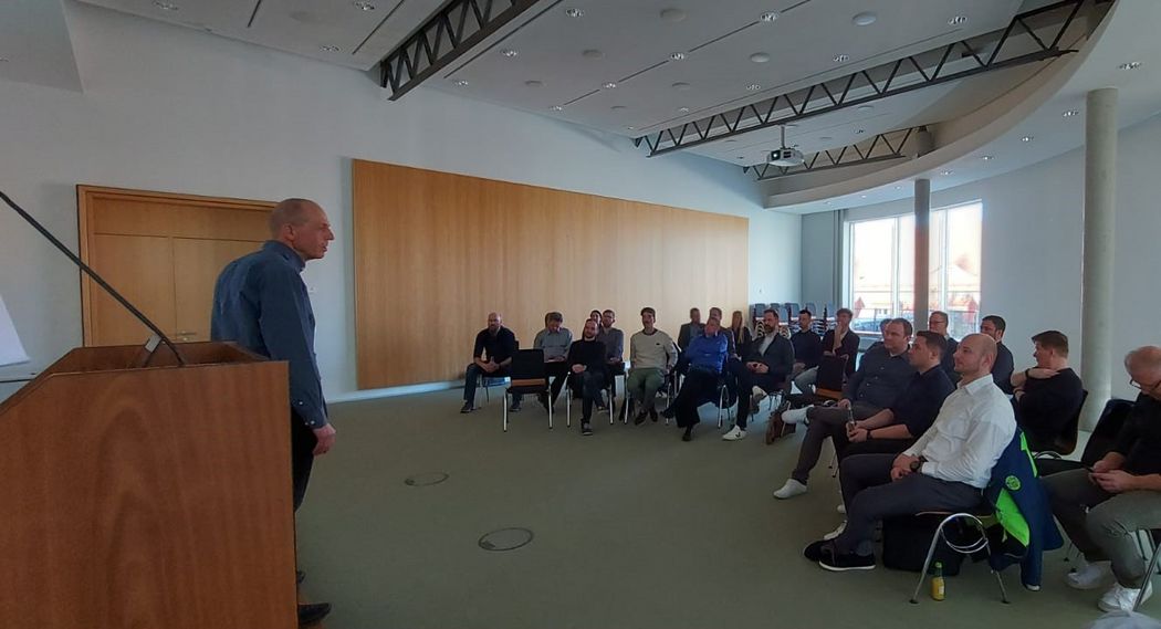 Foto: Teilnehmende einer Veranstaltung sitzen auf Stühlen und hören einem Vortrag zu 
