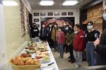 Internationale Studierende blicken auf ein Buffet mit Backwaren. Die Teilnehmer tragen Maske.