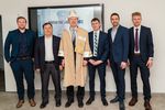 Eine Gruppe Männer nebeneinander steht vor einem Bildschirm