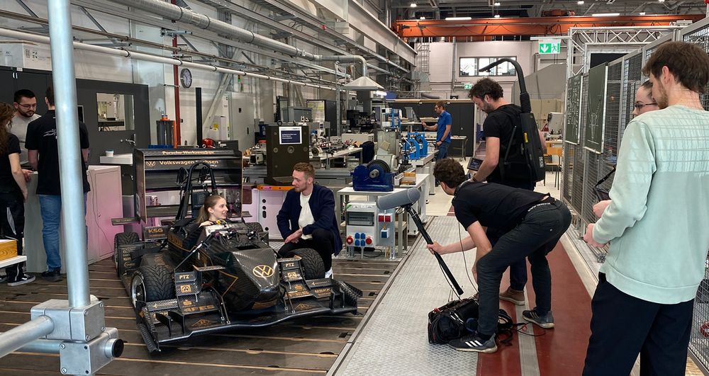 Blick auf das Rennauto vom Racingteam. Im Vordergund ist der Kameramann, der eine Szene filmt