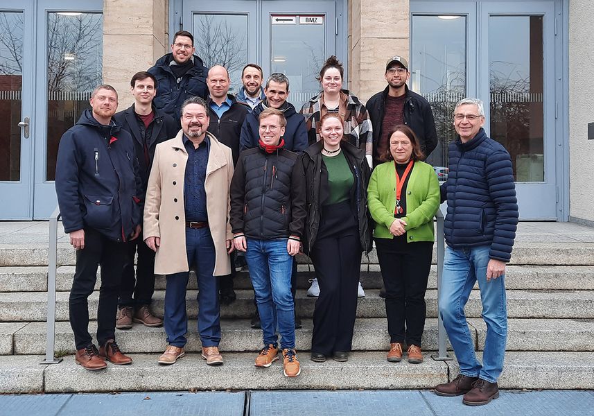 Eine Gruppe von Personen steht auf einer Treppe und blickt in die Kamera. 