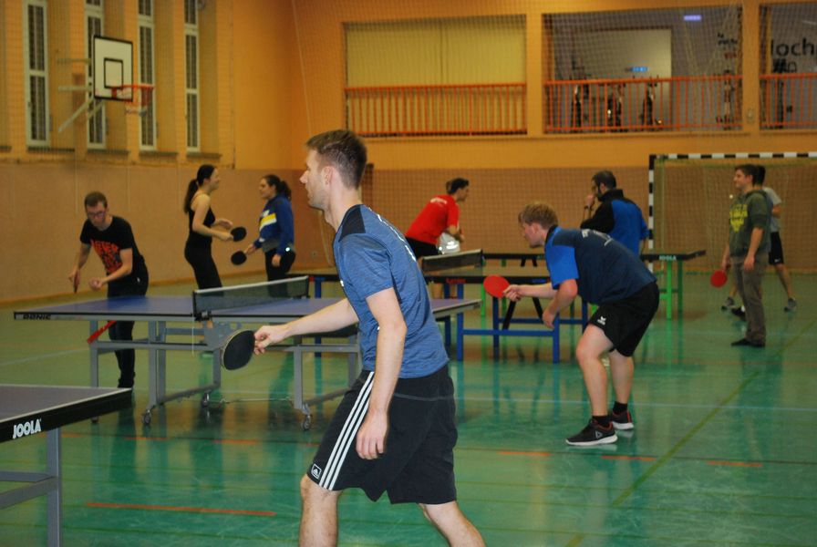 Foto: Tischtennis. Mehrere Spieler spielen in einer Sporthalle.