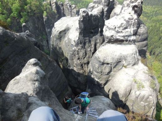 Foto: Klettern. Blick von einem Felsen sitzend nach unten. Zwei weitere Teilnehmer klettern gerade nach oben.