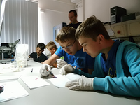 Foto: 4 Jungen in einem Labor experimentieren unter Anleitung.