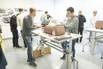 Foto: Studierende stehen an Tischen und modellieren die Modelle von Fahrzeugen.