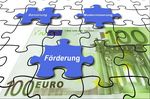 Illustration. Ein 100 Euro Schein als Puzzle dargestellt. In einem Puzzlestein steht Förderung.