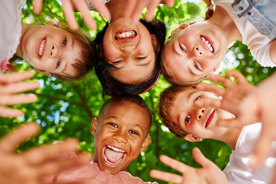 Foto: im Kreis stehende Kinder schauen in die Kamera (Quelle: Robert Kneschke/adobestock )
