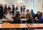 Schplerinnen und Schüler sitzen und stehen in einem Seminarraum und reden in lockerer Athmosphäre miteinander
