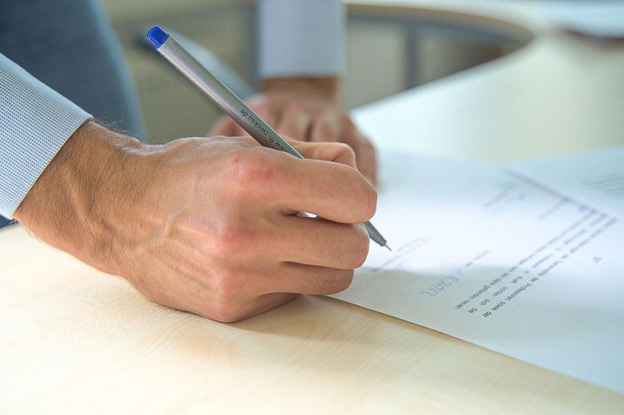 Vorschaubild: Eine Person unterschreibt einen Arbeitsvertrag der WHZ auf einem Tisch im Dezernat Personalangelegenheiten (Quelle: Charlott Wieden)