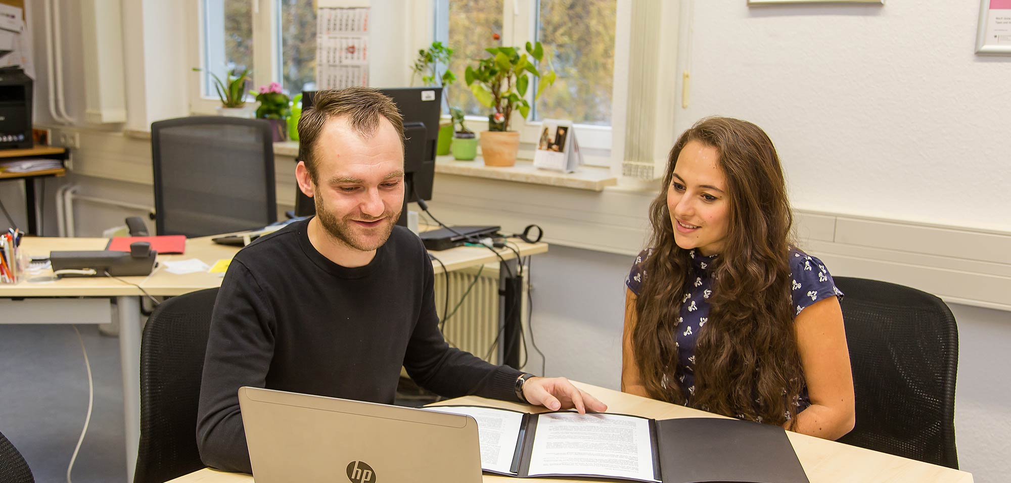 Foto: Titelbild Job, Karriere, Weiterbildung. Ein Berater sitzt mit einer Studierenden an einem Tisch.