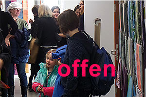 Foto: Mit Aufschrift "offen". Hochschulinformationstag. Ein Frau mit Rucksack und Kind.